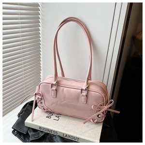 Dettaglio borsa in pelle verniciata rosa con lacci laterali, fiocchi e occhielli in metallo