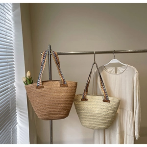 Detail of woven straw tote bags with colorful bohemian jacquard shoulder straps