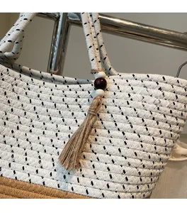 Close-up of handwoven cotton rope beach bag with wood bead tassel and textured weave