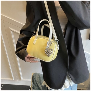 Détail d'un mini sac en cuir jaune vif avec liseré blanc et breloque en forme de cœur