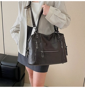 Detail shot of vintage leather tote bag showing multi-zipper pockets and hardware