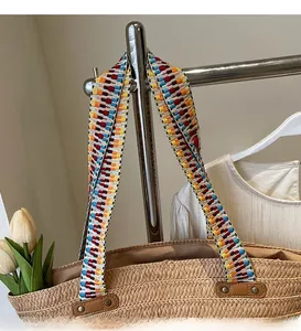 Detail of hand-woven straw tote bag with ethnic style colorful shoulder strap and rivets