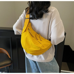 Macro detail of vibrant yellow nylon crossbody bag with woven zipper and strap buckles