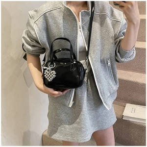 Détail du petit sac carré noir brillant en similicuir avec breloque cœur en perles