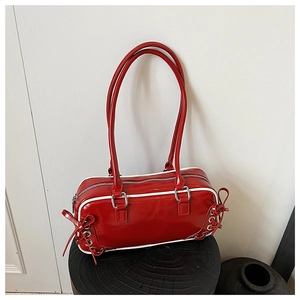 Dettaglio della borsa a spalla in pelle verniciata rossa con profili bianchi e fiocco