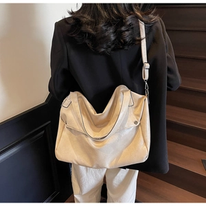 Detail view of cream-white leather tote bag texture and adjustable metal strap buckle
