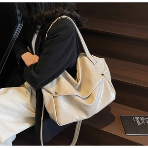 Detail of creamy white oil wax leather tote bag with glossy texture and silver buckles