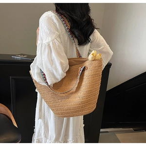 Close-up of large straw tote bag with colorful ethnic embroidered shoulder strap detail