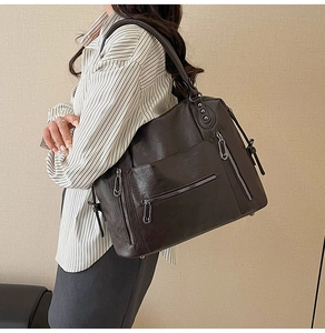 Detail view of large vintage brown leather tote bag with multiple silver zippers