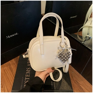 Détail du sac à main crème avec pendentif coeur argenté et bandoulière réglable