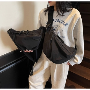 Detail view of black nylon dumpling bag with adjustable wide strap and woven zipper puller