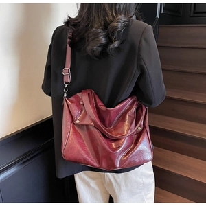 Macro view of burgundy oil-wax leather tote bag showing adjustable strap and texture