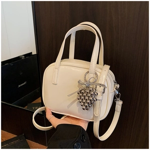 Détail du mini sac bandoulière blanc crème avec un charme de perles argentées et anses