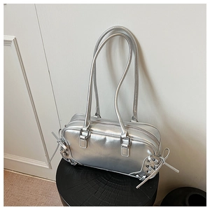 Detail of silver metallic handbag with side ribbon ties and mirror finish on a stool