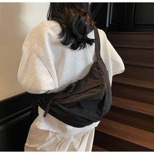 Detailed side view of black crescent nylon crossbody bag worn on a casual outfit