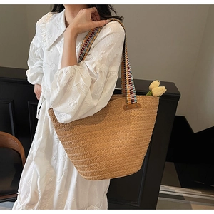 Detail of woven straw tote bag featuring bohemian colorful straps and tulip decoration