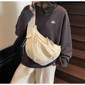 Close-up of lightweight nylon crescent bag in oatmeal beige worn by model on stairs