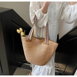 Detail of woven straw tote bag with colorful geometric handle and leather reinforcement