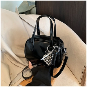 Détail d'un sac à main noir brillant avec perles de cœur argentées et bandoulière amovible
