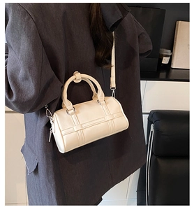Detail of cream white mini barrel bag with crossbody strap on a black blazer