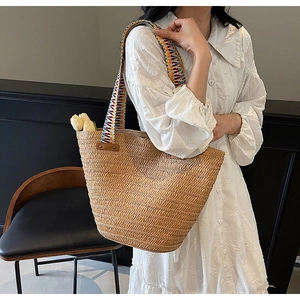 Close-up of a woven straw tote bag with a colorful jacquard embroidered shoulder strap