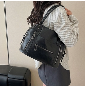 Detail of black vintage faux leather tote bag with functional side zippers and silver studs
