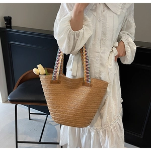 Detail of hand-woven straw tote bag featuring colorful geometric ribbon handles