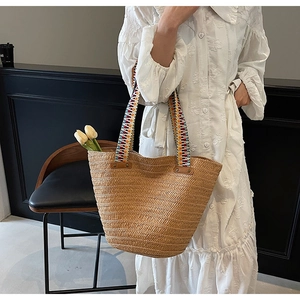 Detailed shot of woven straw tote bag with colorful ethnic geometric handle straps