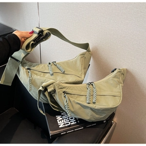 Detail of sage green nylon crescent bag with woven zipper pull and adjustable strap