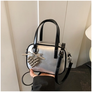 Détail du sac bandoulière argenté avec pendentif en cœur et décoration de ruban