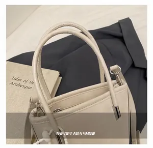 Dettaglio borsa tote beige in pelle con manico arrotondato e ciondolo di perline