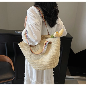 Detail of woven straw tote bag with colorful geometric patterned shoulder strap