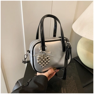 Détail du mini sac carré argenté métallisé avec breloque coeur et poignées noires