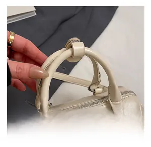 Close-up of cream pillow bag featuring soft leather texture and elegant pearl charm detail