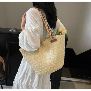 Detail of hand-woven straw tote with vibrant bohemian multi-color beaded shoulder strap