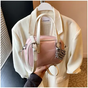 Détail d'un sac en cuir verni rose avec pendentif à perles et finitions métalliques