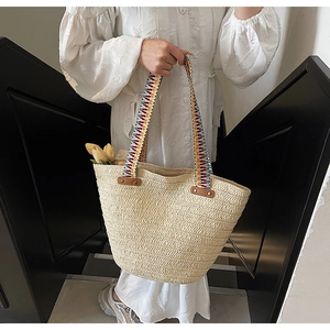 Detail of hand-held straw tote bag with colorful geometric woven handles and tulip decor