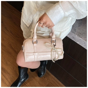 Detailed view of pale pink Boston bag featuring pearl bow charm and silver hardware