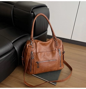 Macro shot of brown pebble grain faux leather bag with silver metallic zippers