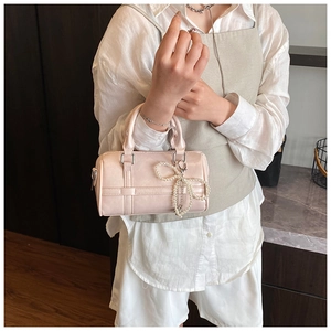Detailed shot of pink cylindrical pillow bag with pearl bow charm and quilted texture