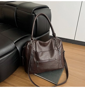 Detail of dark brown vintage faux leather tote with textured finish and metal zippers