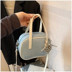 Détail d'un sac à main bleu brillant avec pendentif coeur et finitions blanches contrastées