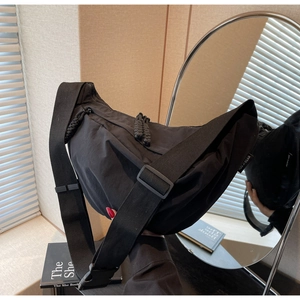 Detail view of large black crescent nylon crossbody bag with wide adjustable shoulder strap