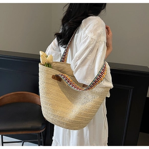 Close-up of cream woven straw tote bag with colorful striped handles and tulip accents