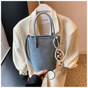 Detail van blauwgrijze emmertas met parelhanger en Fashion & Bags reliëflogo