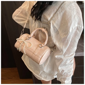 Detail of pink cylindrical pillow bag with pearl bow charm worn by a model