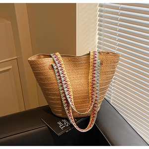 Detail of hand-woven straw tote bag featuring a colorful ethnic patterned wide strap