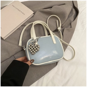 Petit sac à main bleu clair avec pendentif cœur sur fond de costume marron élégant