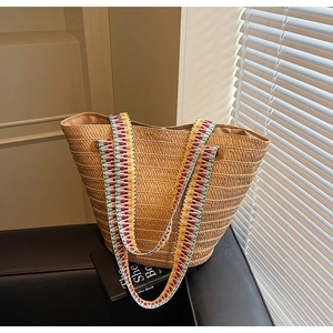 Detailed shot of large woven straw tote bag with colorful ethnic patterned ribbon handles