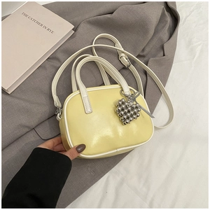 Détail du sac à bandoulière en similicuir jaune clair avec liseré blanc et breloque cœur